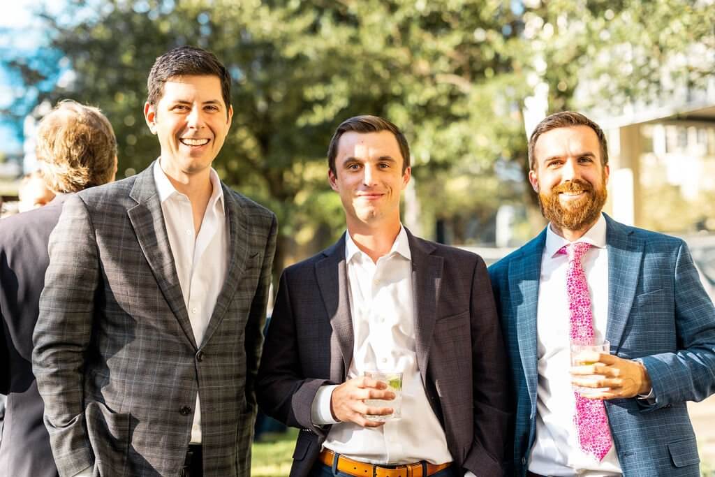 three men with drinks smiling