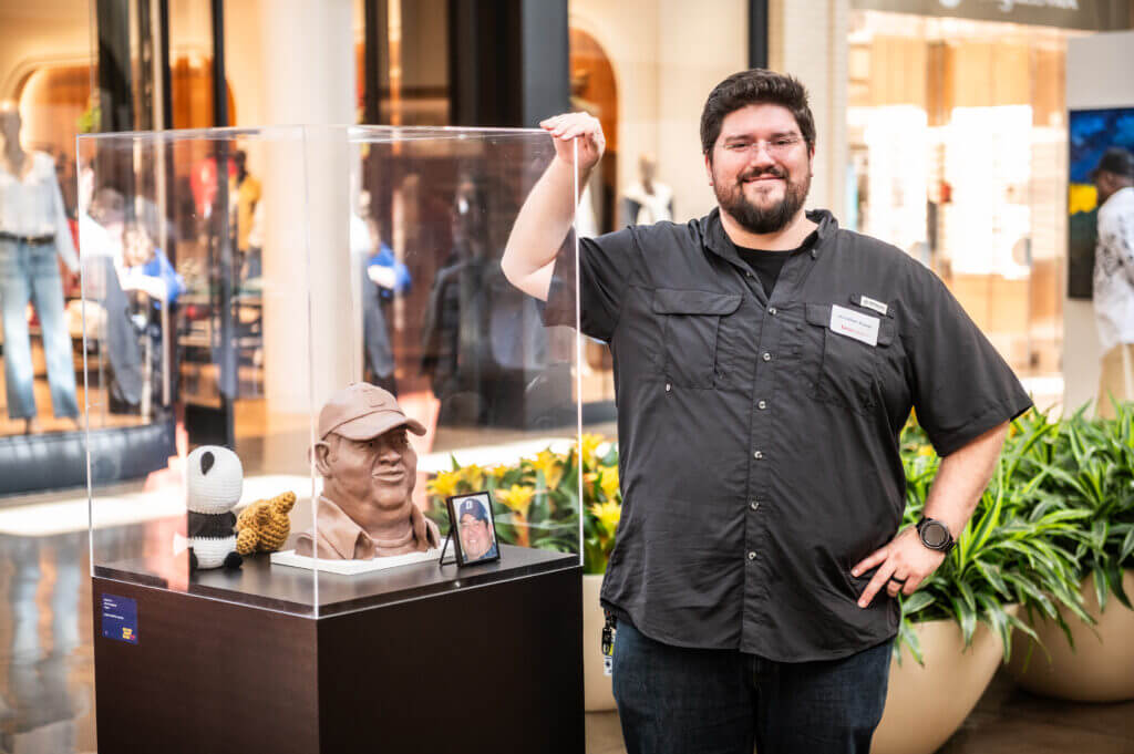 man smiling by sculpture